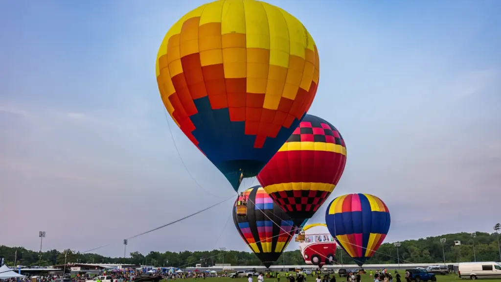 Kolorowe balony na ogrzane powietrze przygotowują się do lotu nad zieloną murawą w Kielcach.