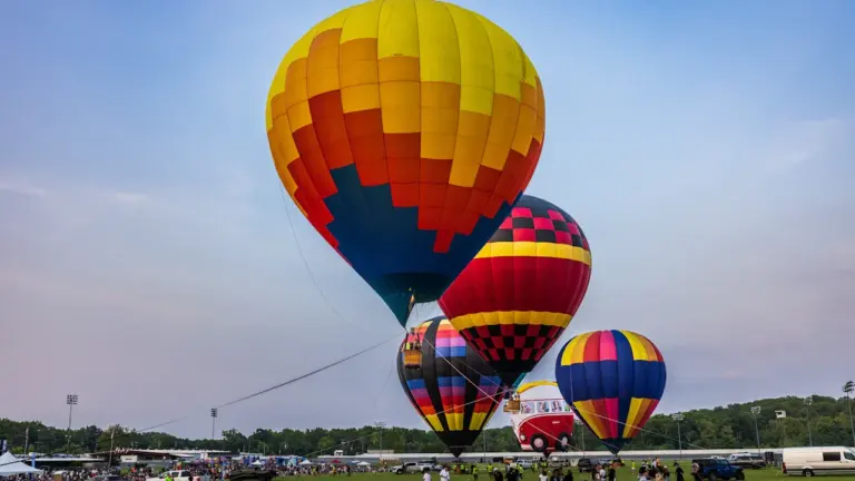 Kolorowe balony na ogrzane powietrze przygotowują się do lotu nad zieloną murawą w Kielcach.