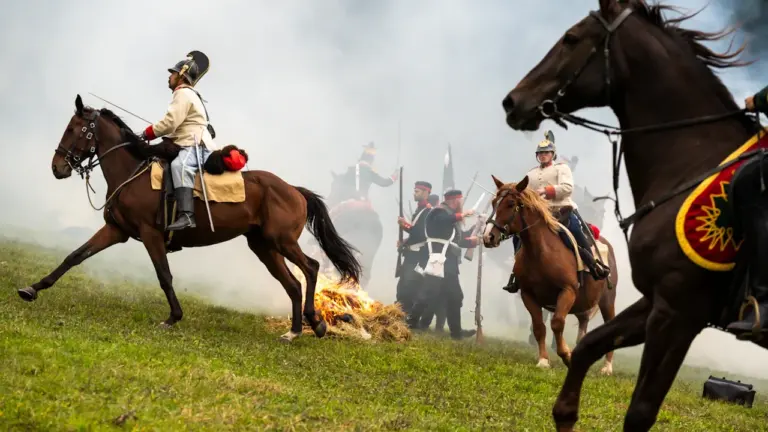 Rekonstrukcja historycznej bitwy z XVIII wieku z udziałem kawalerii i piechoty na polu.