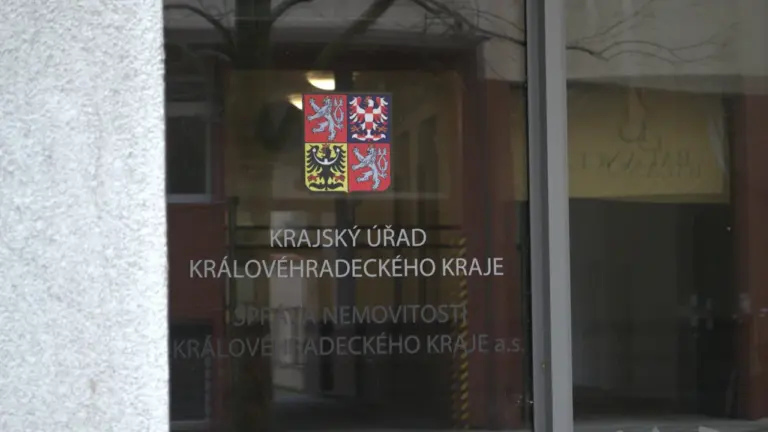 Szklane drzwi wejściowe do urzędu regionalnego z godłem państwowym i napisami informacyjnymi.