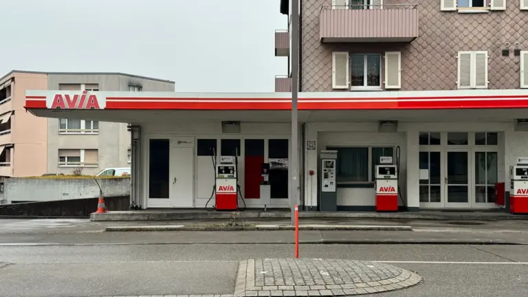 Nowoczesna stacja paliw z wyraźnym oznaczeniem przy drodze w miejskim otoczeniu.